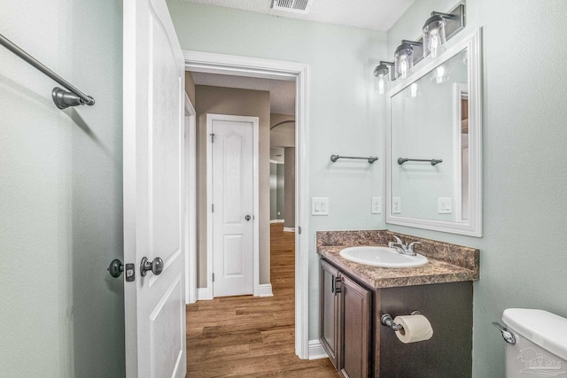 bathroom with wood-type flooring, toilet, and vanity