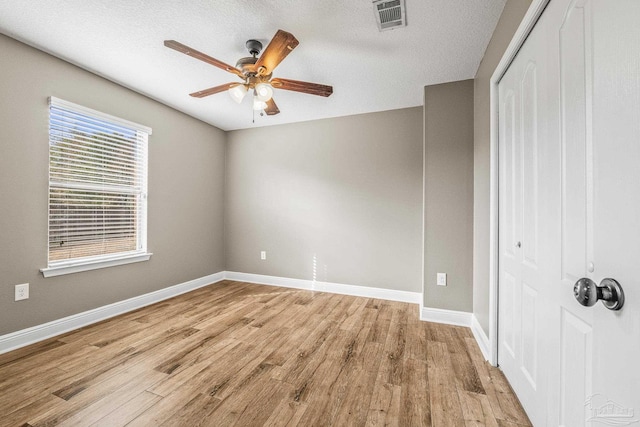 unfurnished bedroom featuring ceiling fan, a closet, a textured ceiling, and light wood-type flooring