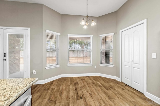 unfurnished dining area featuring light hardwood / wood-style floors and a chandelier