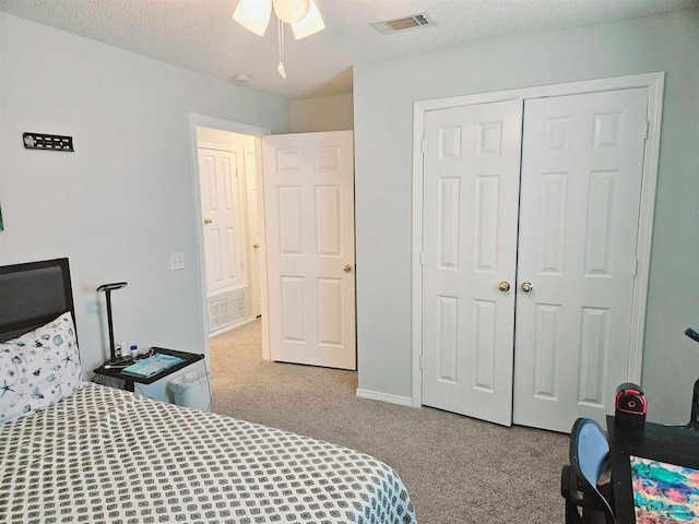 carpeted bedroom with a closet, a textured ceiling, and ceiling fan