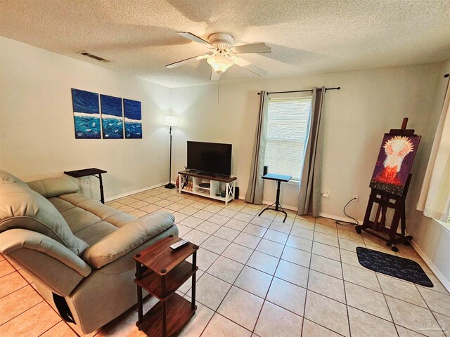 living room featuring a textured ceiling, ceiling fan, and light tile patterned floors