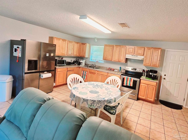 kitchen with light brown cabinets, sink, light tile patterned floors, appliances with stainless steel finishes, and a textured ceiling