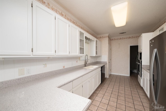 kitchen featuring appliances with stainless steel finishes, white cabinetry, a textured ceiling, crown molding, and sink