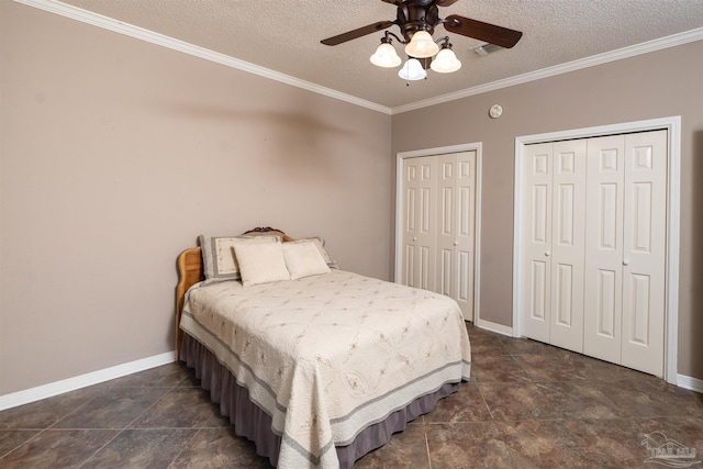 bedroom featuring ornamental molding, two closets, a textured ceiling, and ceiling fan