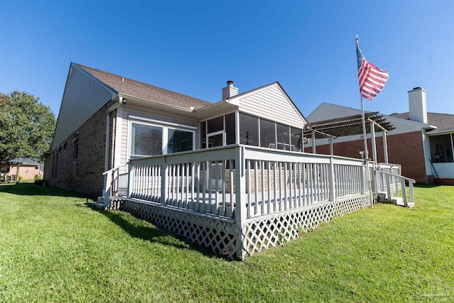 rear view of property featuring a wooden deck, a lawn, and a sunroom