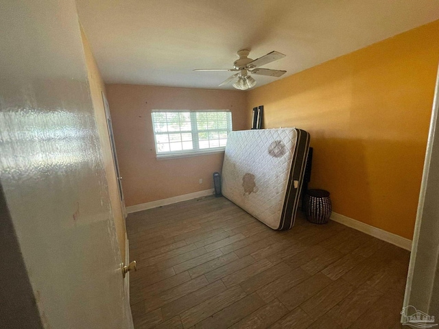 unfurnished bedroom featuring dark wood-type flooring and ceiling fan