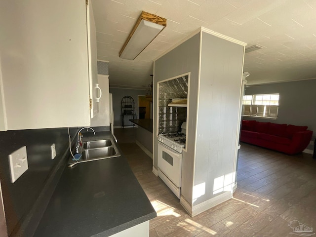 kitchen with white cabinetry, sink, dark hardwood / wood-style flooring, ornamental molding, and white gas stove