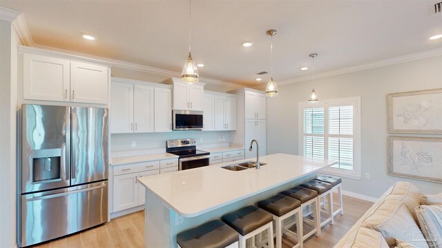 kitchen featuring white cabinetry, sink, stainless steel appliances, and decorative light fixtures