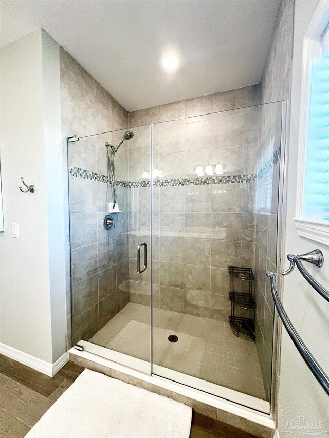 bathroom with wood-type flooring and an enclosed shower