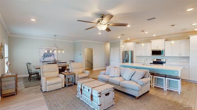 living room featuring ceiling fan with notable chandelier, light hardwood / wood-style floors, crown molding, and sink