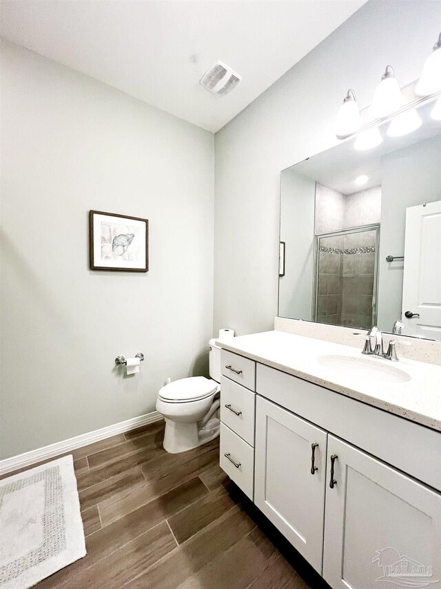 bathroom with vanity, a shower with shower door, toilet, and hardwood / wood-style flooring