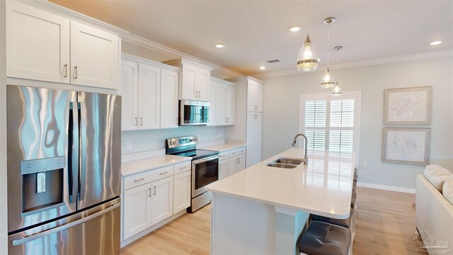 kitchen featuring an island with sink, white cabinets, pendant lighting, stainless steel appliances, and sink