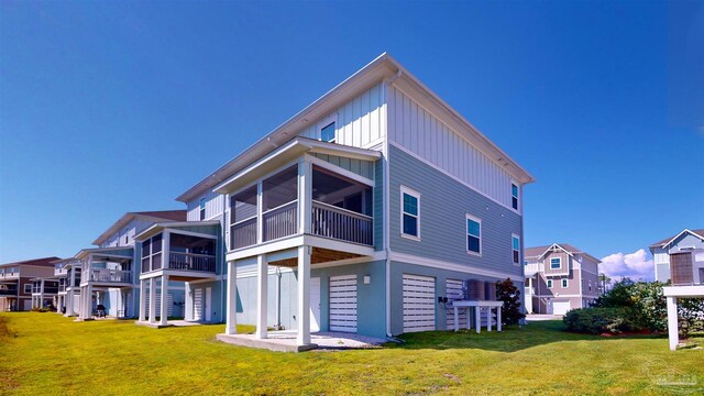 rear view of property featuring a sunroom, a lawn, and a patio