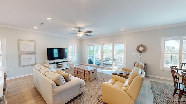 living room featuring light wood-type flooring, crown molding, ceiling fan, and plenty of natural light