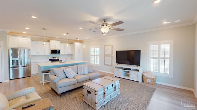 living room featuring light hardwood / wood-style flooring, ceiling fan, sink, and crown molding