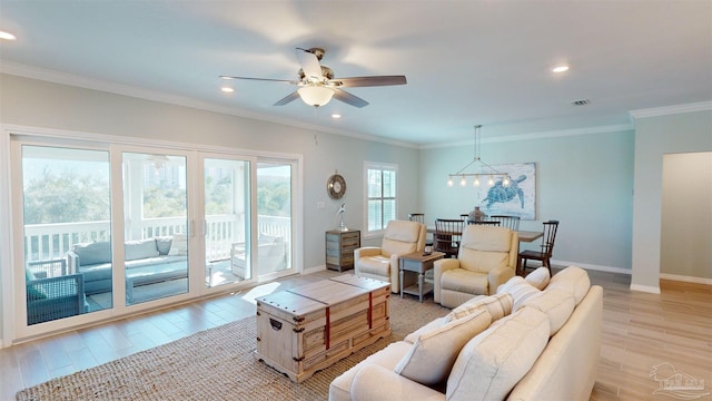 living room featuring ceiling fan with notable chandelier, light wood-type flooring, and crown molding