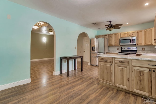 kitchen featuring arched walkways, light brown cabinets, a ceiling fan, light countertops, and appliances with stainless steel finishes