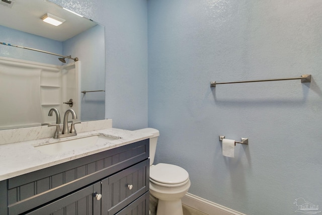 full bath featuring baseboards, vanity, toilet, and walk in shower