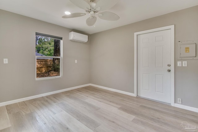 empty room with light wood finished floors, ceiling fan, baseboards, and a wall mounted AC