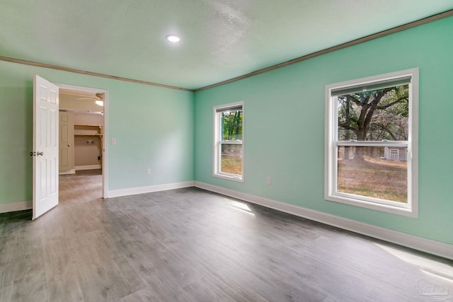 empty room featuring baseboards, crown molding, and wood finished floors