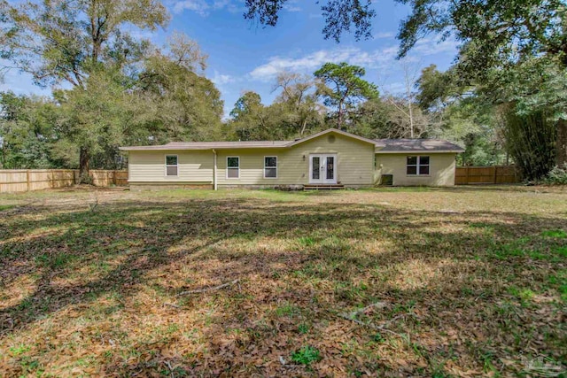 rear view of property featuring french doors, fence, and a lawn