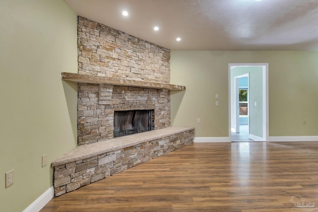 unfurnished living room with recessed lighting, a fireplace, wood finished floors, and baseboards