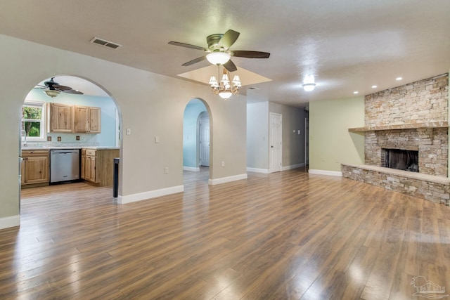 unfurnished living room with a ceiling fan, visible vents, a fireplace, and wood finished floors