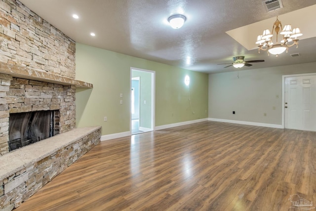 unfurnished living room featuring baseboards, visible vents, wood finished floors, a textured ceiling, and a fireplace