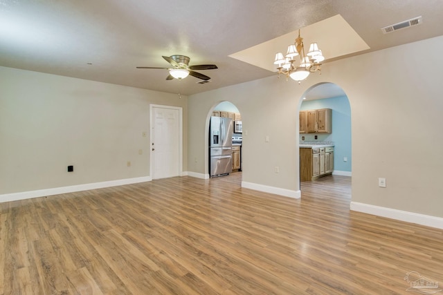 unfurnished living room with light wood-style floors, baseboards, visible vents, and arched walkways