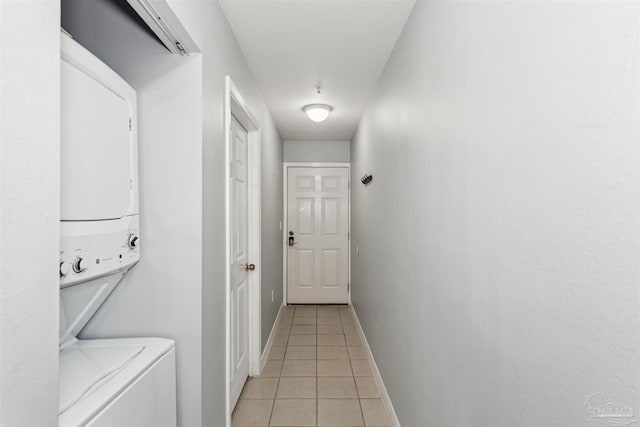 laundry room featuring stacked washer / dryer and light tile patterned flooring