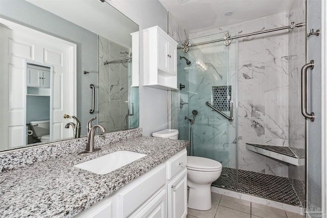 bathroom featuring a shower with door, vanity, and toilet