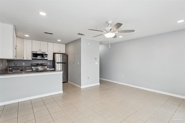 kitchen with sink, appliances with stainless steel finishes, white cabinetry, kitchen peninsula, and dark stone counters