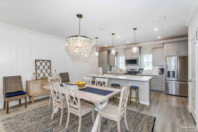 dining area featuring crown molding, sink, and light hardwood / wood-style flooring