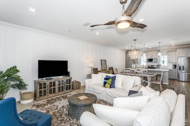 living room with dark wood-type flooring, ceiling fan, and ornamental molding