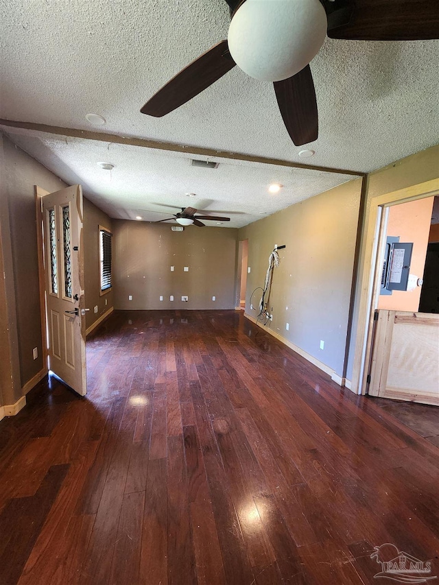 unfurnished living room with ceiling fan, dark hardwood / wood-style flooring, and a textured ceiling