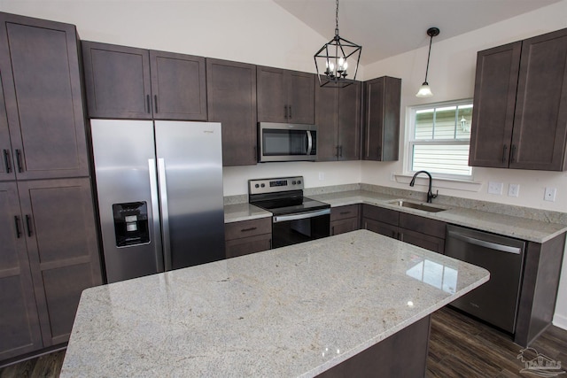 kitchen featuring light stone countertops, appliances with stainless steel finishes, sink, hanging light fixtures, and lofted ceiling