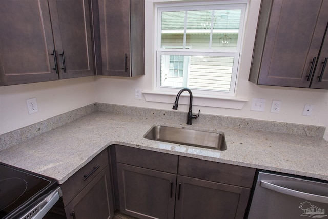 kitchen featuring dishwasher, dark brown cabinetry, light stone countertops, and sink