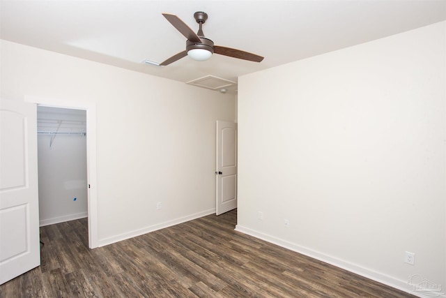 unfurnished bedroom featuring ceiling fan, dark hardwood / wood-style flooring, a walk in closet, and a closet