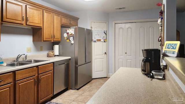 kitchen with appliances with stainless steel finishes, sink, and light tile patterned floors