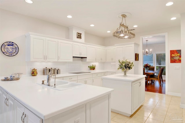 kitchen featuring white cabinetry, sink, decorative light fixtures, and kitchen peninsula