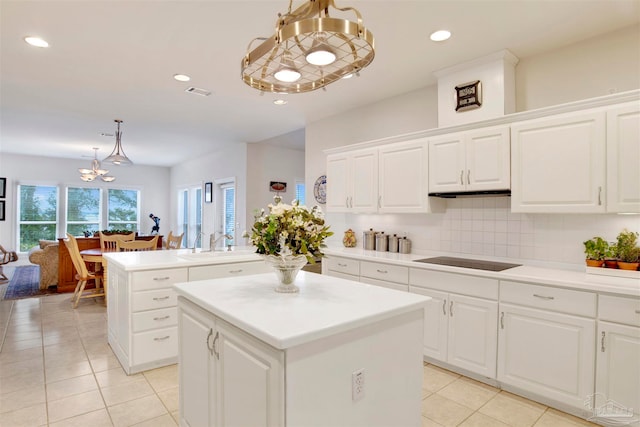 kitchen with white cabinetry, decorative light fixtures, a chandelier, black electric cooktop, and a kitchen island