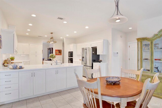 kitchen featuring stainless steel refrigerator with ice dispenser, white cabinetry, sink, and hanging light fixtures