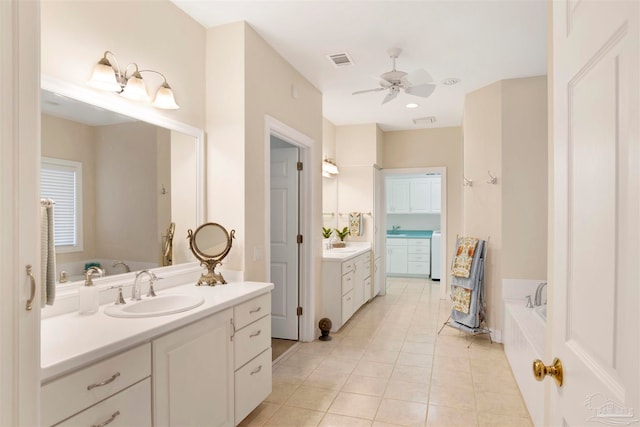 bathroom with tile patterned flooring, vanity, tiled bath, and ceiling fan