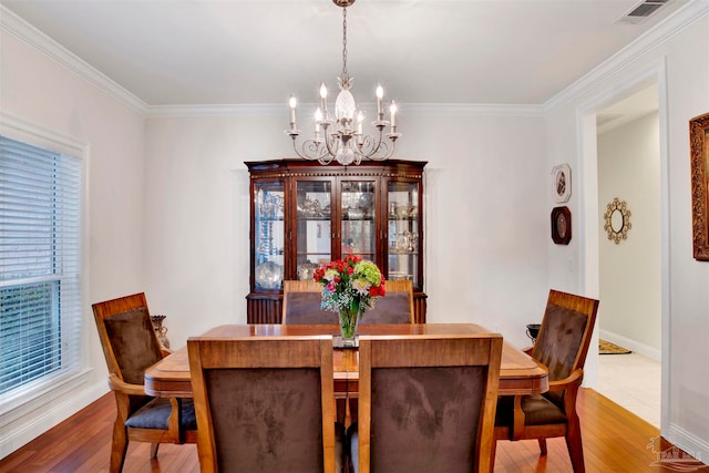 dining space with hardwood / wood-style floors, a notable chandelier, and ornamental molding