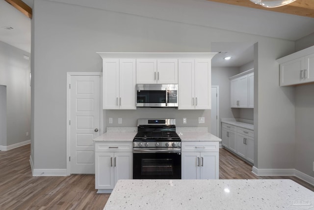 kitchen featuring white cabinetry, appliances with stainless steel finishes, light stone counters, and light hardwood / wood-style flooring