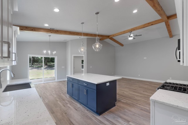 kitchen with sink, blue cabinetry, beam ceiling, a kitchen island, and decorative light fixtures