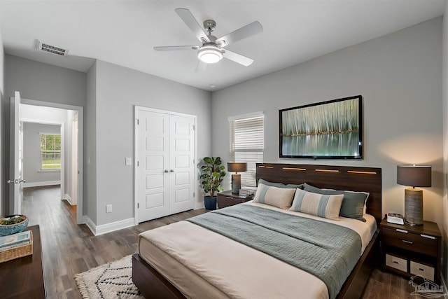 bedroom with dark wood-type flooring, ceiling fan, and a closet