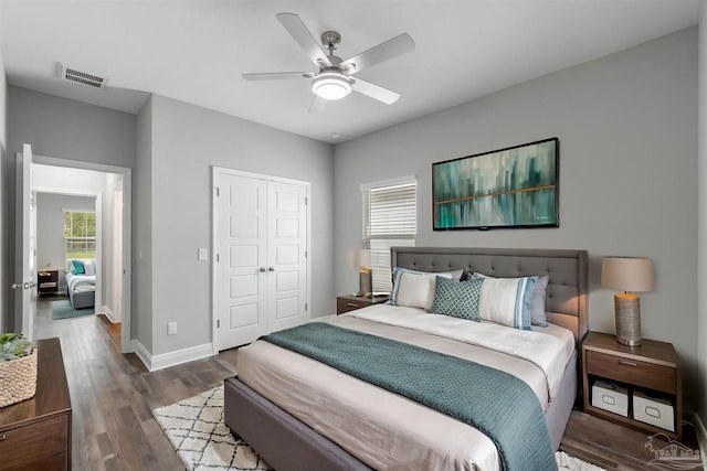 bedroom with dark hardwood / wood-style floors, ceiling fan, and a closet