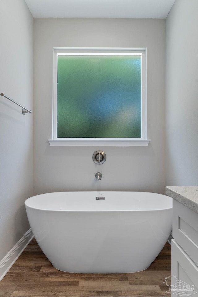 bathroom featuring hardwood / wood-style flooring, vanity, and a bath