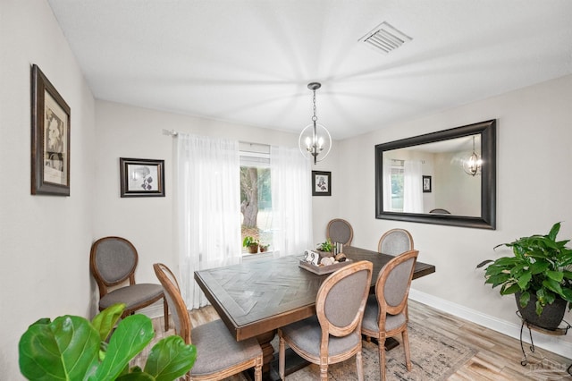 dining space with wood-type flooring and an inviting chandelier